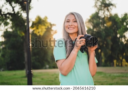 Portrait of attractive cheerful grey-haired woman spending time making capture art snap landscape evening sunset outdoors