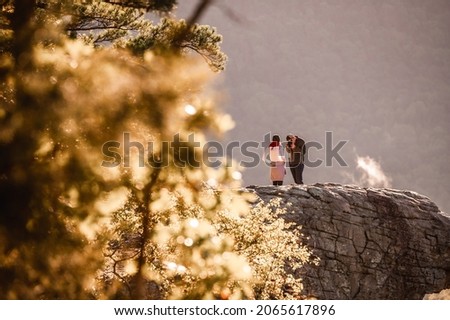 A young, attractive, couple on the edge of Whitaker Point, also known as Hawksbill Crag, near Kingston, AR during a sunrise hike in the Natural State. Royalty-Free Stock Photo #2065617896
