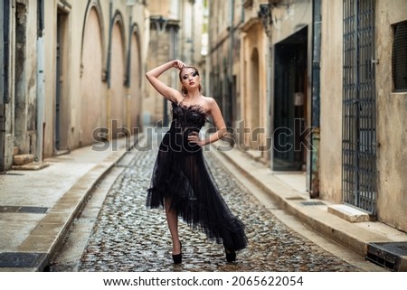 A stylish bride in a black wedding dress in the ancient French city of Avignon. A model in a black dress.