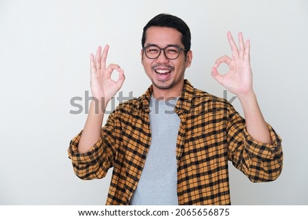 Adult Asian man showing excited face expression while giving two OK finger sign