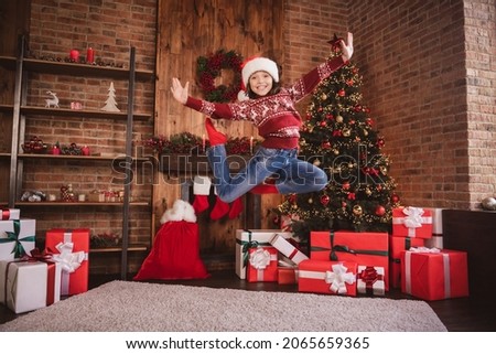 Photo of sporty energetic crazy little girl enjoy flight jump wear pullover santa headwear socks indoors
