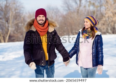 Photo portrait of cheerful couple walking together holding hands in snowy park smiling
