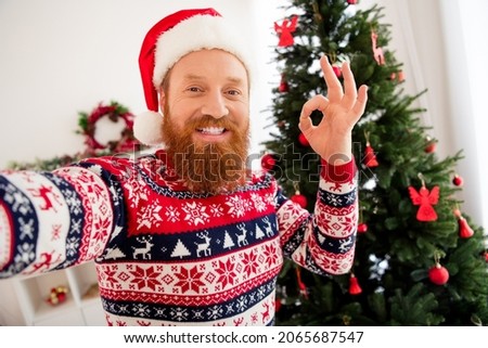 Photo of smiling handsome guy in santa hat take selfie shooting blogging showing okay sign gesture celebrate merry christmas