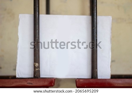 A blank white sign board inside two iron bars for advertising by writing any text or design and the background blur