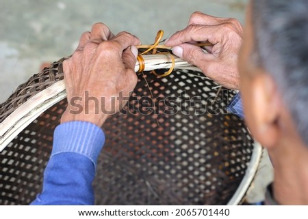 Ninh Binh, Vietnam - 25 Oct 2021: Vietnamese craftsman weave baskets with natural materials: rattan and bamboo Royalty-Free Stock Photo #2065701440