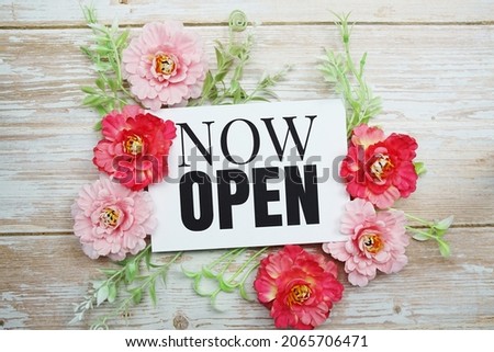 Now Open text  with Blooming flower on wooden background