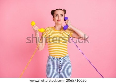 Portrait of pretty person arms hold two vintage handset doubtful face isolated on pink color background