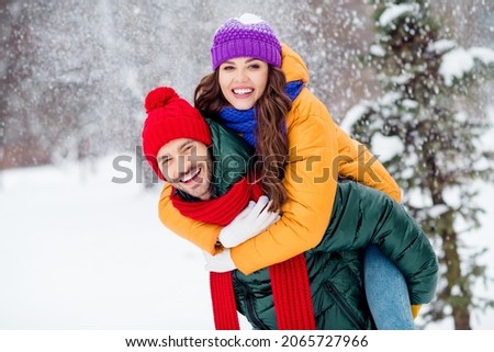 Photo of pretty adorable girlfriend boyfriend dressed vests smiling cuddling riding back walking snow outdoors forest Royalty-Free Stock Photo #2065727966