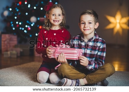 Two happy children in new year eve with presents near New Year Tree at home