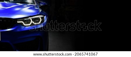 Front view of the LED headlights modern blue car on black background,