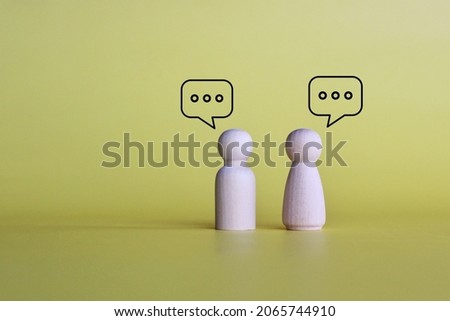 Wooden dolls with speech bubble of message and chatting on yellow background with copy space. Social media interaction and chat concept.