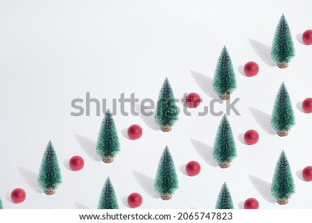 Arranged green New Year and Christmas tree with red bauble on a white pastel background. Pattern. Copy space.