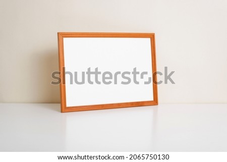 Horizontal photo frame mock-up with empty space for branding or text standing against wall indoors. Picture template, minimalistic decor.