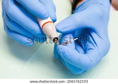 An ultrasonic scaler for removing dental plaque in the hands of the dentist close-up. Royalty-Free Stock Photo #2065762193