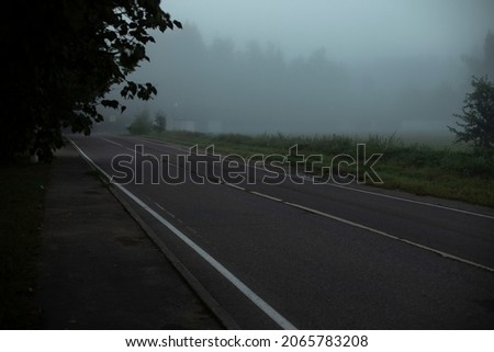 The road is in the fog. Highway without cars. Rural road in the morning.