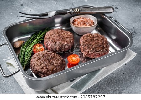 Burger beef meat steak patties with herbs. Gray background. Top view.