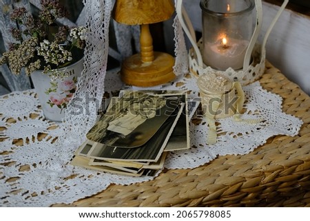 burning candle, lace, old chest of drawers shabby chic, stack of retro photos of 50-60s, reverse side of photo, flowers, concept of family tree, genealogy, connection with ancestors, memories of youth