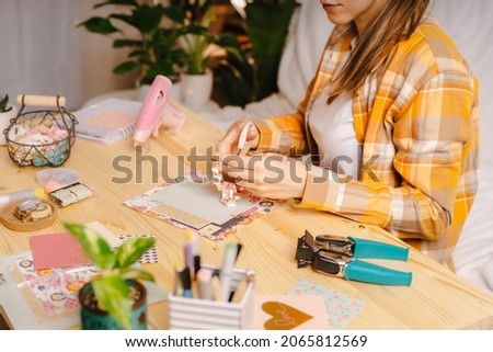 Cropped shot of women making homemade scrapbooking album from paper. DIY, hobby concept, gift idea, decor with handcraft attributes, home production, the process of creation, creativity. Royalty-Free Stock Photo #2065812569