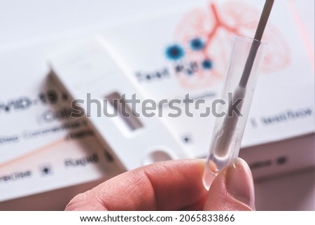 Covid-19, SARS‑CoV‑2 antigen test kit, one step coronavirus antigen rapid test, saliva swab, 1 test box with imagine of lungs and with fingers of a girl testing, close up Royalty-Free Stock Photo #2065833866