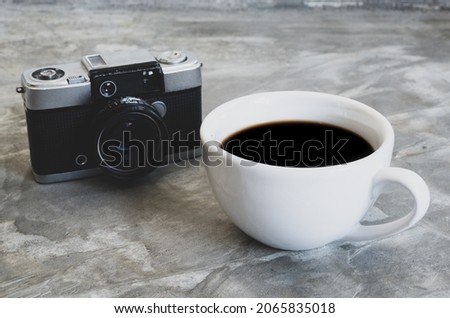 photo above white cup hot coffee ิblack Americano without sugar it is popular to drink in morning to help them stay awake  ready to work. and classic camera on a table cement pattern Loft color