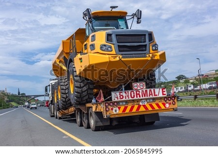 New heavy large tipper earthworks truck vehicle on abnormal e  transport trailer traveling delivery route. Royalty-Free Stock Photo #2065845995