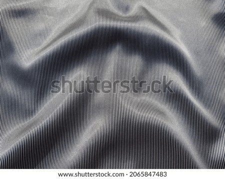 Wavy surface of silk fabric with striped black and white print (macro, texture).