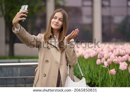 Girl doing selfie on the background of tulips flowers in the city center