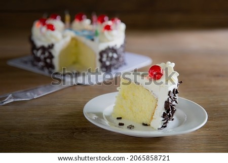 Piece of birthday cake cut and put in white dish on wooden table,  Choose focus and free space for message., Still life image

