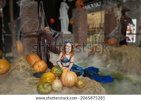 a little girl in a mermaid costume for the holiday of evil spirits Halloween. Sweets or life in the costume of a terrible mermaid