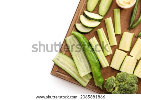 Board with different green vegetables on white background