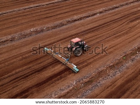 Peat Harvester Tractor on Collecting Extracting Peat. Mining and harvesting peatland. Area drained of the mire are used for peat extraction. Drainage and destruction of peat bogs. Royalty-Free Stock Photo #2065883270