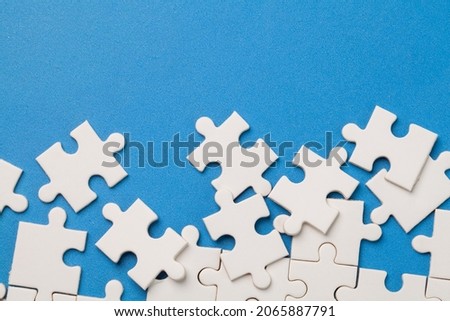scattered white jigsaw puzzle pieces on blue background. Royalty-Free Stock Photo #2065887791