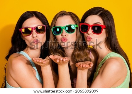 Photo of young pretty lovely girls in sunglass send you air kiss enjoying summer vacation isolated on yellow color background