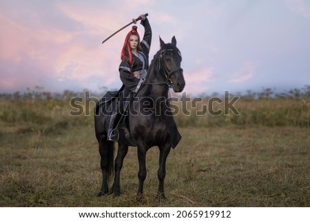 A warrior girl in a black kimono on a black horse with a katana in her hands