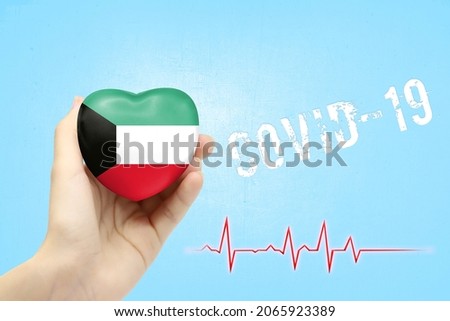 A girl is holding a toy in the shape of a heart with the flag of Kuwait, a concept of health care during the covid-19 coronavirus pandemic