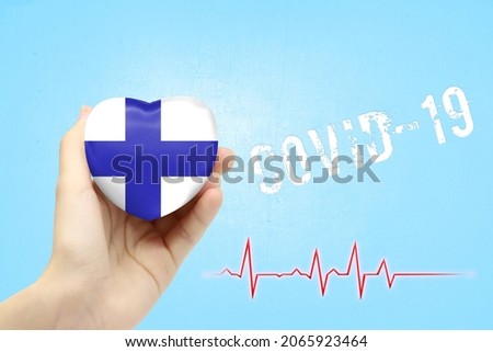 A girl is holding a toy in the shape of a heart with the flag of Finland, a concept of health care during the covid-19 coronavirus pandemic