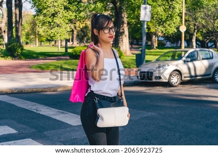 A Portrait of a beautiful Latin woman walking down the street with shopping bags. Shopping concept.