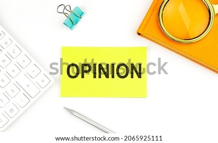 Sticker with the text OPINION on the white background, near calculator and notebook