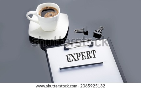 EXPERT text on paper sheet with coffee on black background