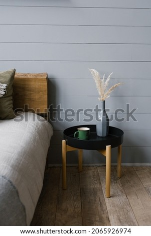 A vase of dried flowers and a mug on the Scandinavian-style bedside table in the bedroom.