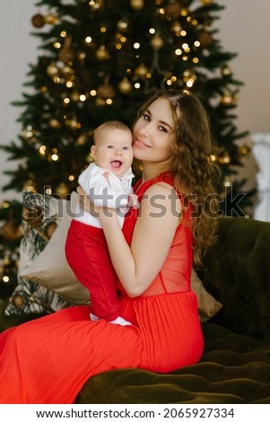 Happy Christmas celebration of a young mother and little son in the living room at the Christmas tree