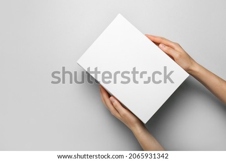 Hands with blank cardboard box on light background Royalty-Free Stock Photo #2065931342