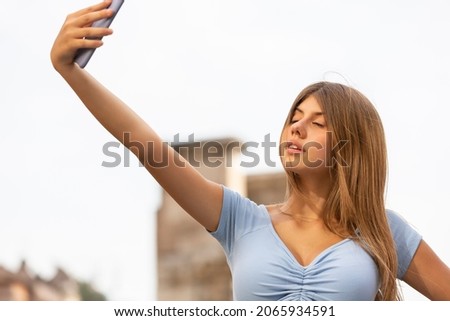 Young woman taking selfies with her smartphone outdoors