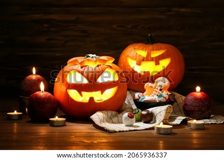 Carved Halloween pumpkins, sweets and candles on dark background
