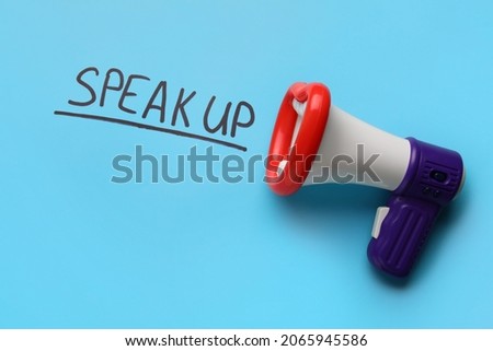 Toy megaphone and text SPEAK UP on color background