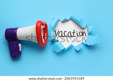 Toy megaphone and word VACATION visible through torn color paper