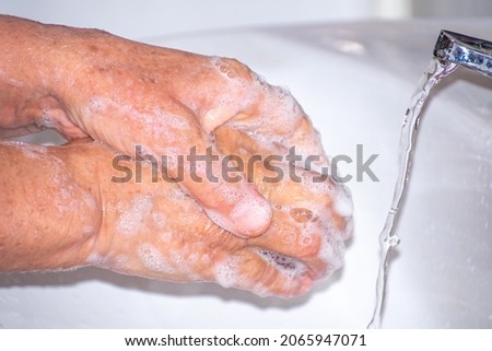 Old woman washing her hands with soap