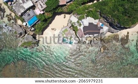 View from above rocks lounge on the cliff blend with blue sea in Suluban beach Bali. Taken by drone.