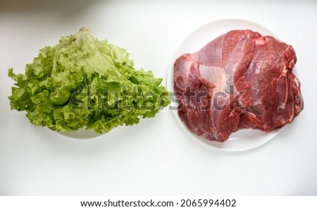 piece of raw beef and lettuce on wooden background