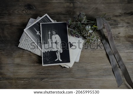 stack of retro monochrome photographs of 50-60s on natural wooden table, photo of child, dried flowers, concept of family tree, genealogy, connection with ancestors, memories of youth, childhood